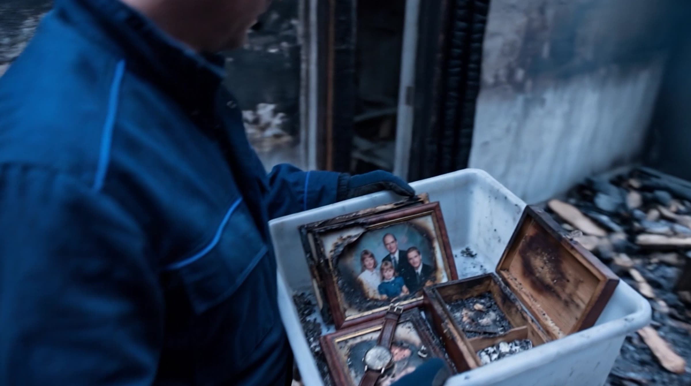 RMO technician carrying a bin of family photos out of a fire-damaged room